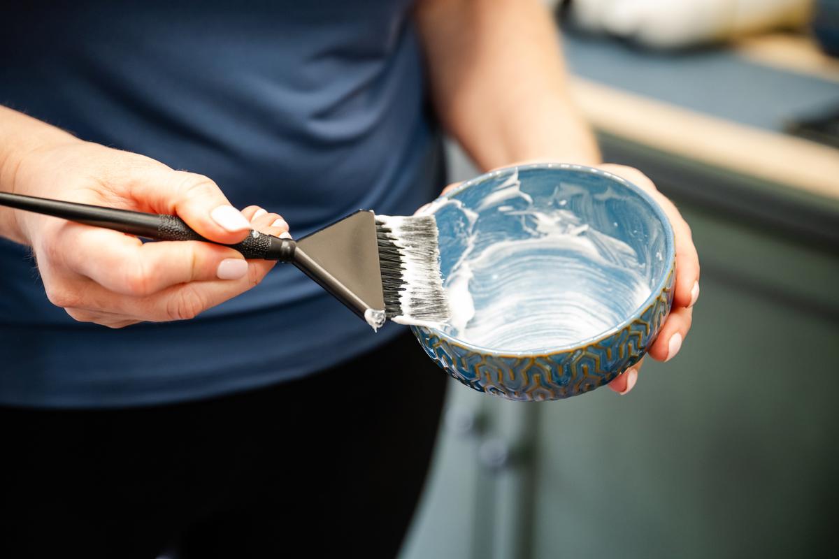 Hairstylist mixing a bowl of lightener for a balayage service in Dallas, TX.